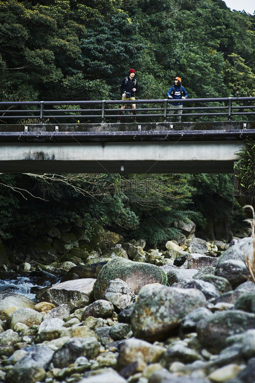 徒步旅行的两个男性在山林中的桥上休息图片