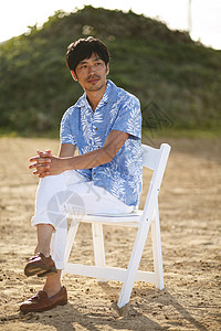 坐在海边沙滩上的男性图片