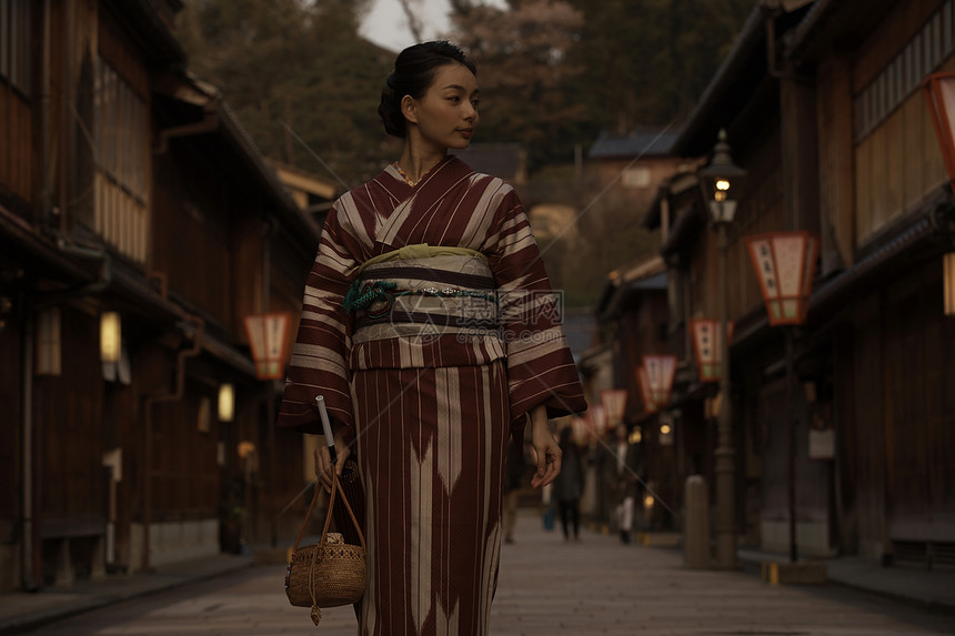 穿着和服的妇女走在光线昏暗的街头图片