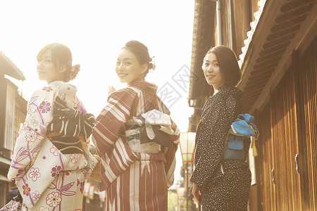 三个女孩微笑着穿着和服在街上背影图片