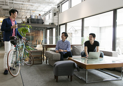 推着自行车和同事沟通交流的商务男士图片