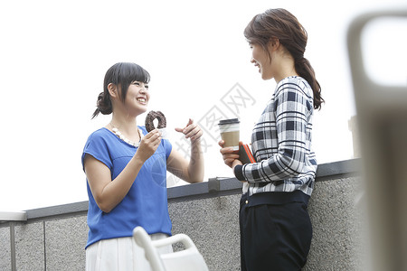 两个甜甜圈商务女性休息时间在户外喝咖啡背景