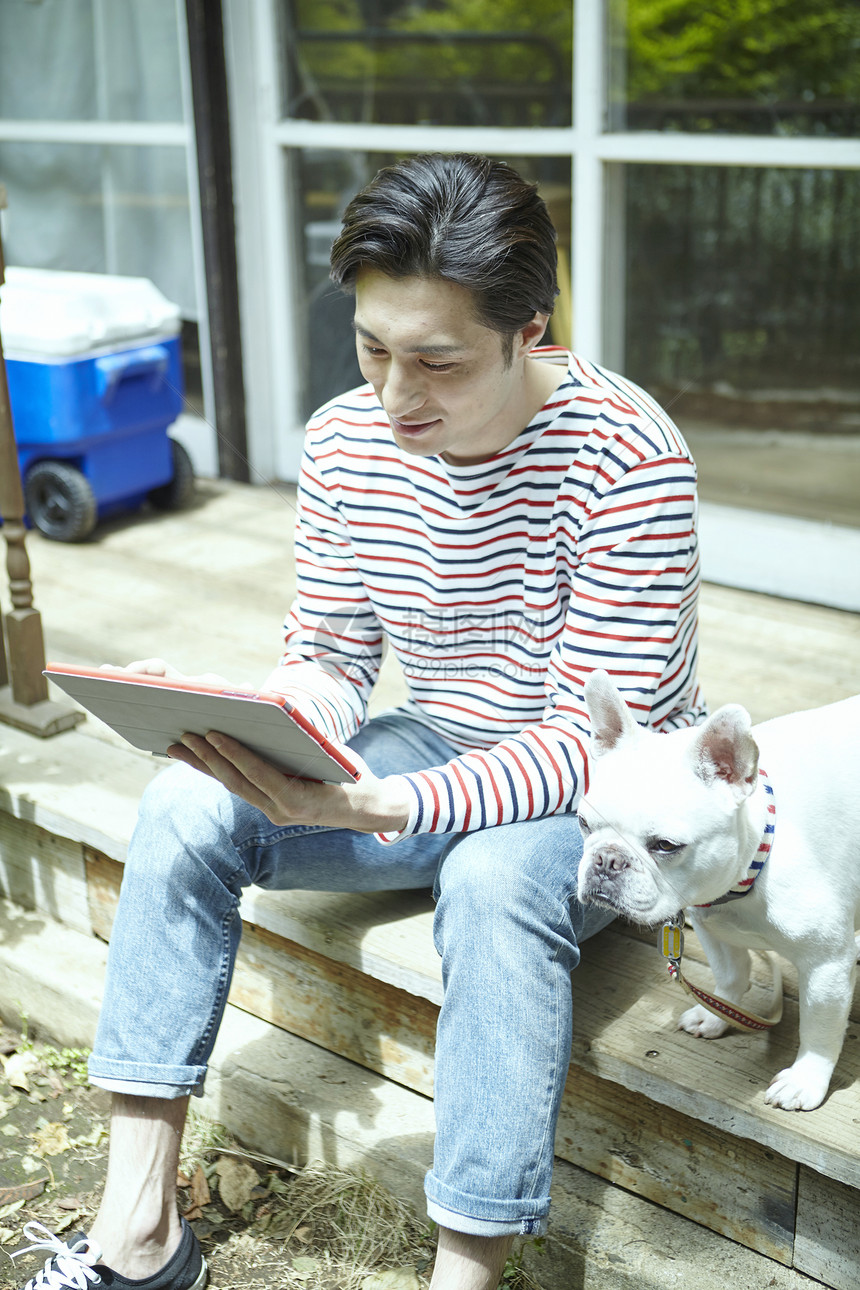 男人坐在台阶上阅读享受阳光与狗相伴图片