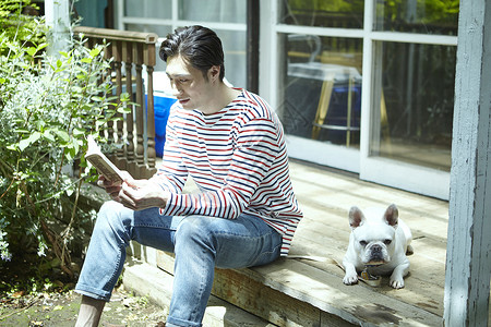 年轻男性与宠物在屋外玩耍看书图片