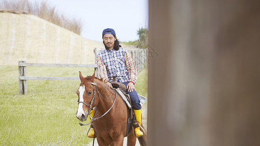 在牧场上骑马的男子图片