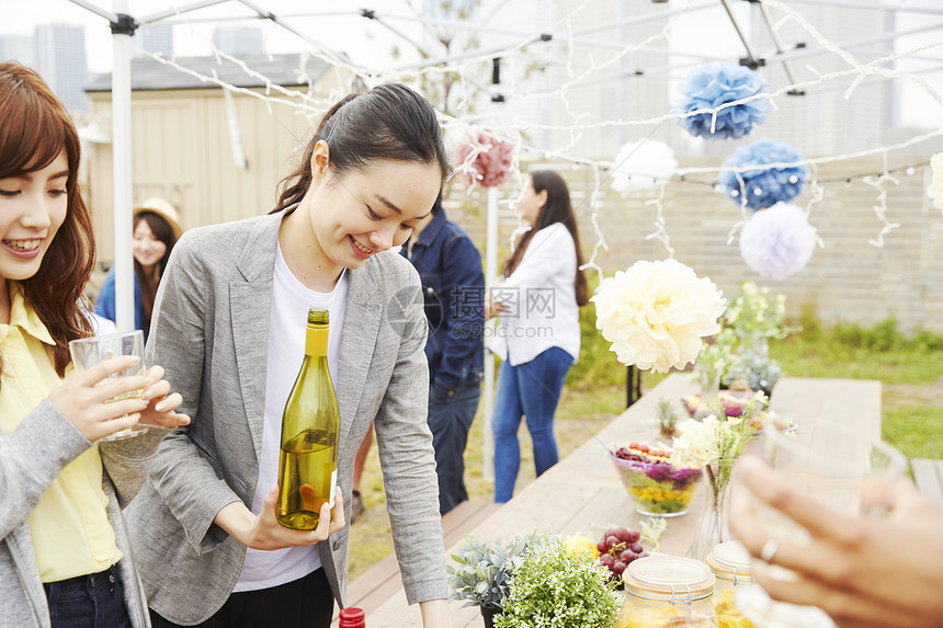 户外烧烤派对上拿酒女人的形象图片