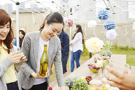 户外烧烤派对上拿酒女人的形象图片