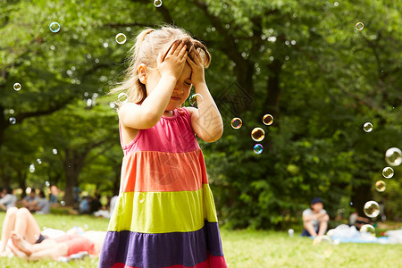 户外公园里玩肥皂泡泡的小女孩图片