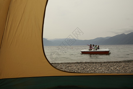 帐篷外湖上坐脚踏船的远足家庭图片