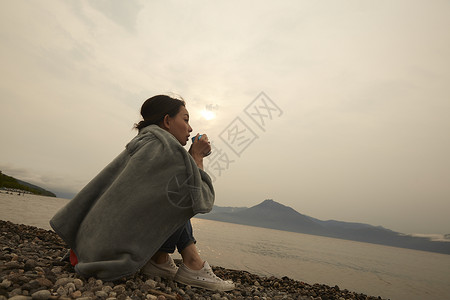 湖边拿着水杯独自旅行的女生肖像图片