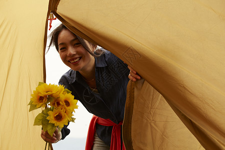微笑掀开帐篷的拿花束的女人图片