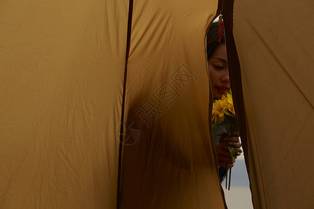 黄昏捧着花站在帐篷外的女人图片