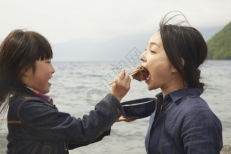 女孩在海边喂妈妈吃牛肉图片