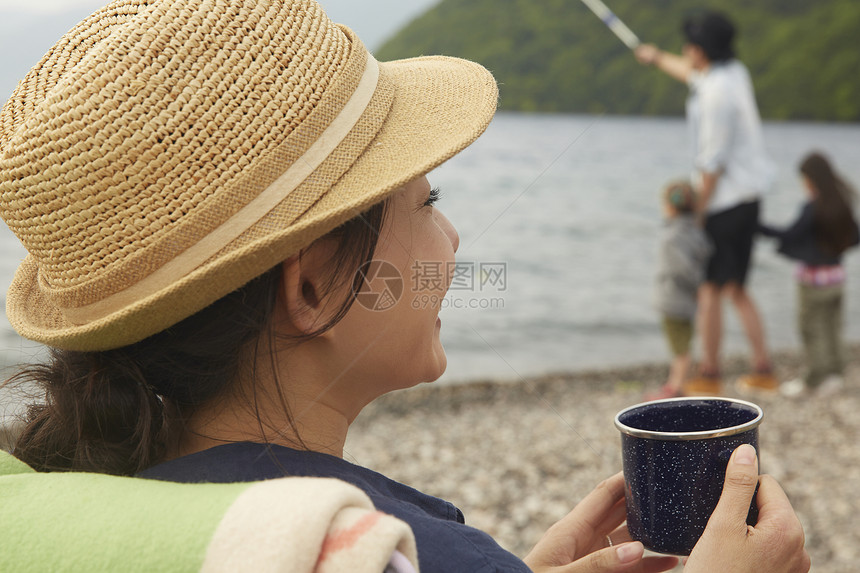 湖边喝茶的女生喝远处钓鱼的3人图片