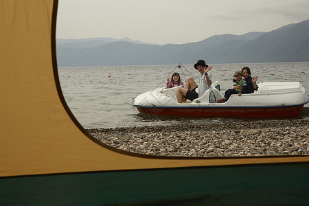 帐篷外坐脚踏船的4人高清图片