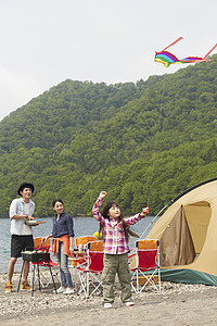 湖边露营烧烤放风筝的3人图片