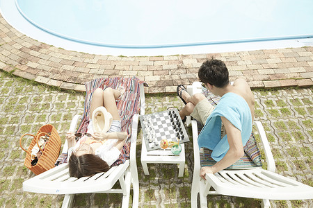 夏日情侣在泳池旁躺椅上休息图片