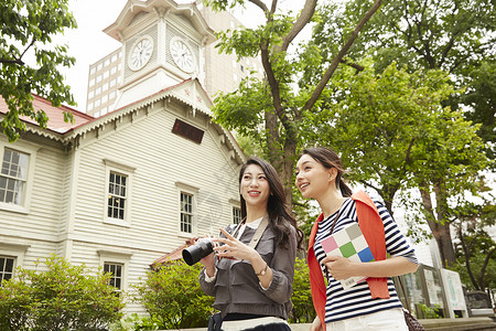 札幌钟楼两个女生带着相机结伴旅游背景
