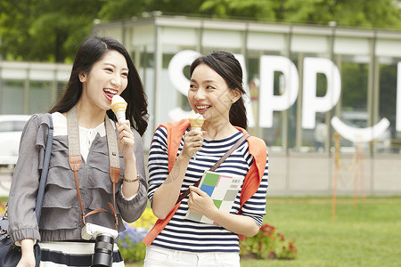 吃冰激凌带着相机旅行的2个女性高清图片