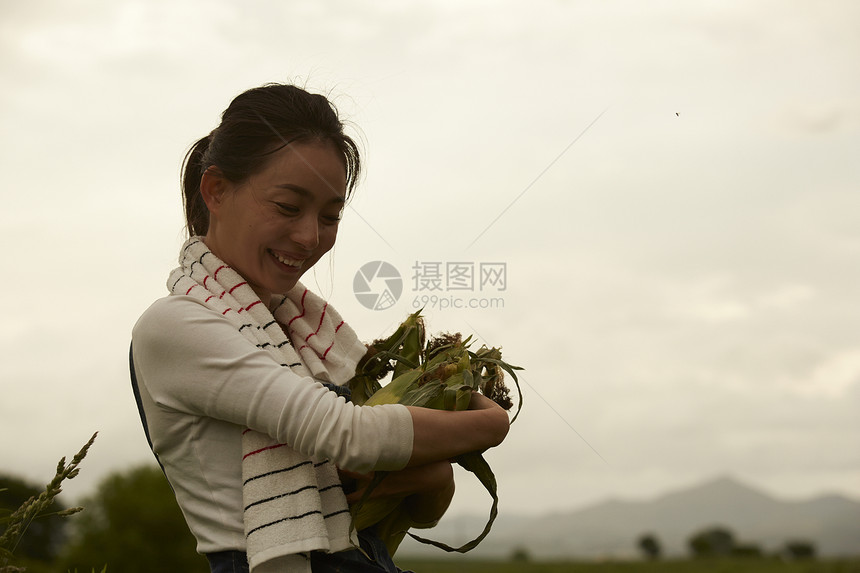 收获新鲜玉米的农民女青年图片