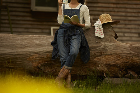 坐在农场大树上喝茶看书的农业女孩图片