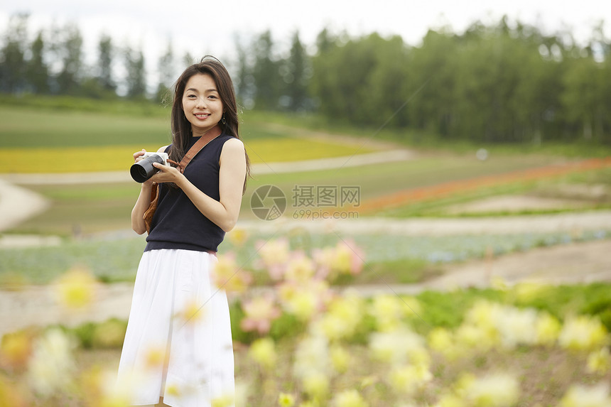 花丛中手持相机看向镜头的长发女孩图片