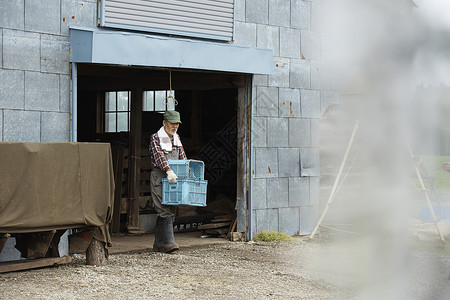 老农民在农场搬运货物图片