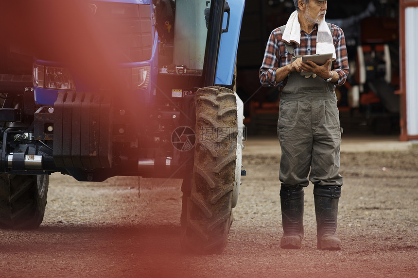 站在拖拉机旁做记录的农夫图片