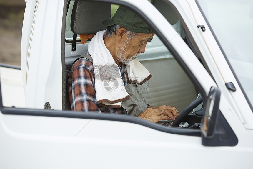 老人坐在农用轻卡车上用笔记本电脑图片