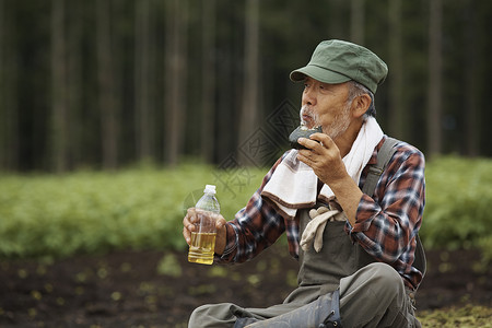 老人坐在农田里休息喝水图片