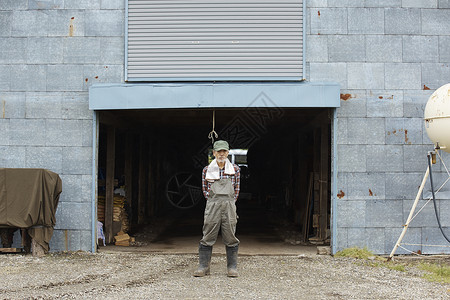 农场车间前站立的农夫肖像图片