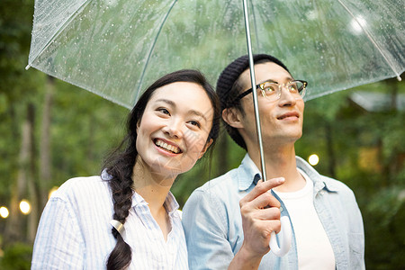 雨天在林间撑伞散步的情侣图片