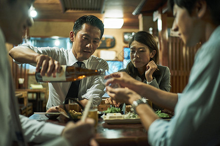 客户答谢晚宴居酒屋内给好友倒酒的男士背景