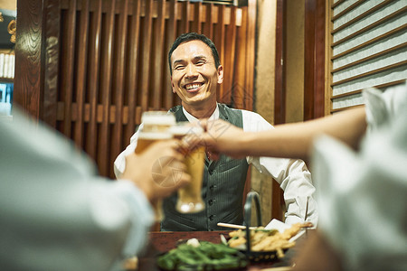 居酒屋餐桌上碰杯的好友图片