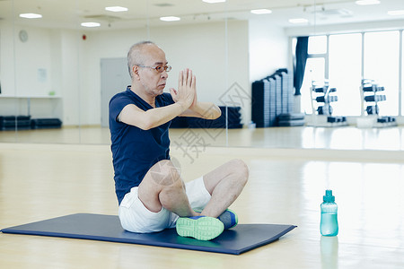 室内瑜伽垫上练瑜伽的中年男子图片