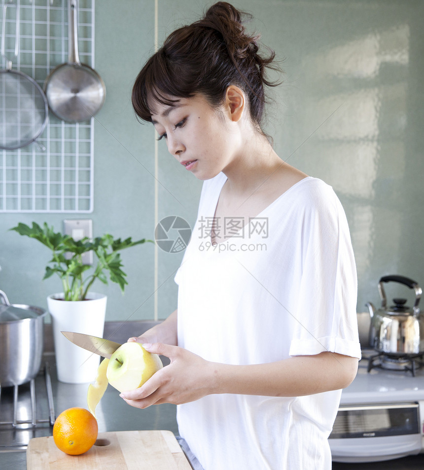 在厨房削苹果的女性图片