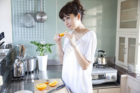 厨房吃橙子的居家女性图片