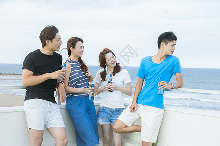 在海边喝酒聊天的青年朋友快乐的高清图片素材