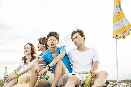 坐在海滩上喝酒的青年人积极高清图片素材