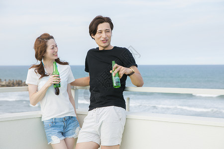 海边度假喝啤酒的情侣高兴高清图片素材