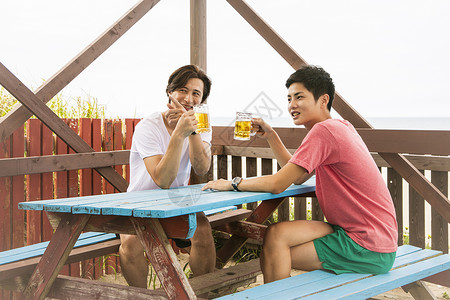 海边度假小屋喝啤酒的男性图片