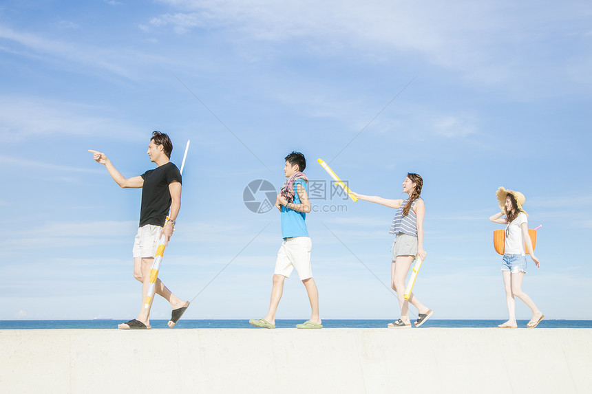 沿着海岸行走的青年游客图片