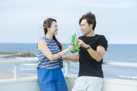 海边天台上情侣度假喝酒享受日本人高清图片素材