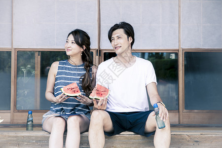 一个男人和一个女人坐在海边吃西瓜图片
