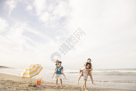 在海滩边背着女朋友行走的两对情侣图片