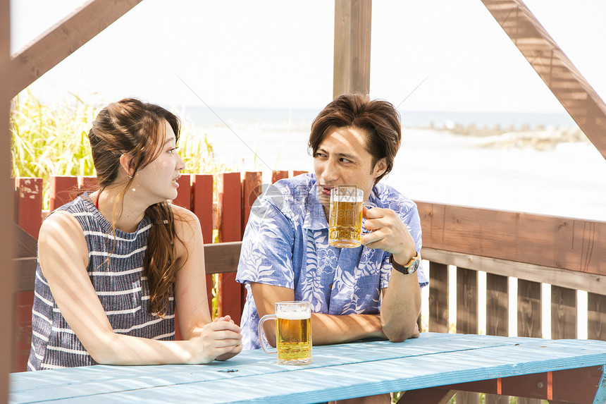 夏日海边喝酒聊天的情侣图片