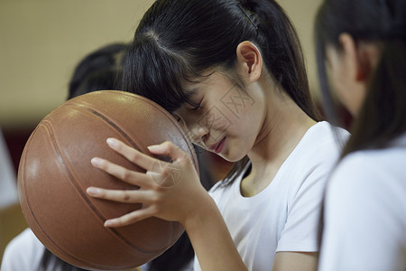 将额头抵在篮球上的女学生图片