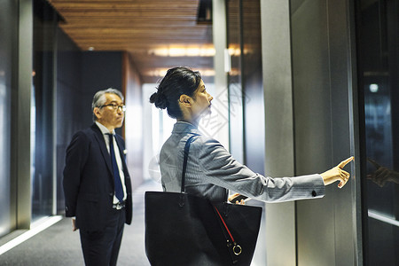 办公楼电梯厅按电梯按钮的女白领与男商人图片