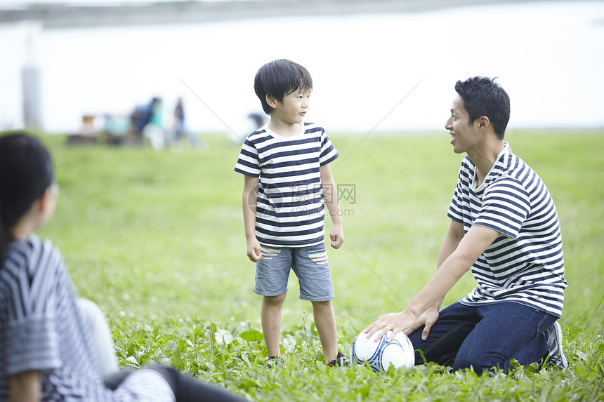 草地上玩耍踢球的父子图片