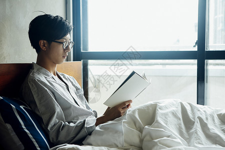 躺在床上看书的男性图片